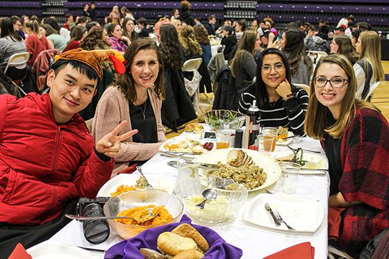 Photo of international students at a 波胆网站 harvest dinner, 吃饭时对着镜头微笑