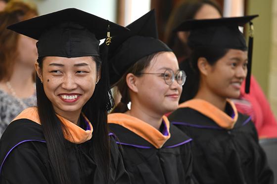 Photo of three 波胆网站 international students at graduation in caps and gowns
