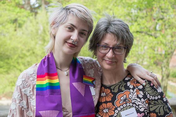 图为一名英国波胆网站的毕业生穿着彩虹披肩, 把胳膊搭在父母或监护人的肩膀上
